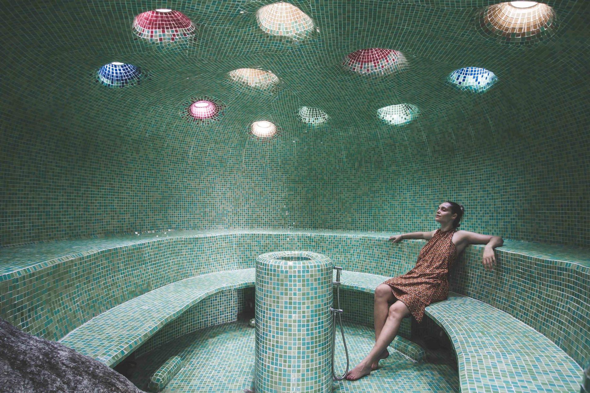 A guest resting in Kamalaya’s tiled steam cave, under coloured glass skylights