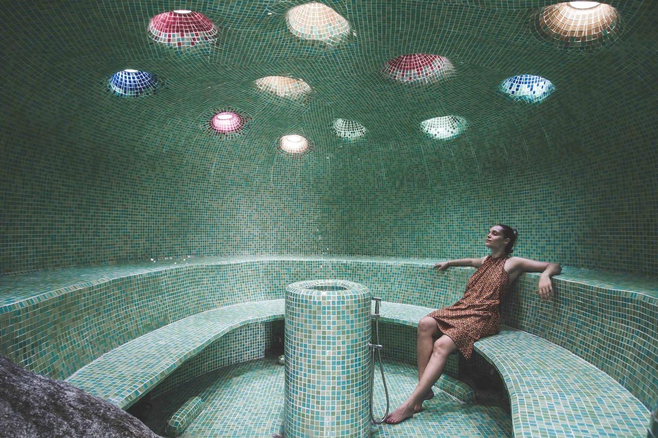 A guest resting in Kamalaya’s tiled steam cave, under coloured glass skylights