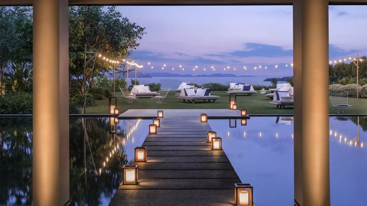 Lanterns along a walkway across the water at COMO Point Yamu at dusk