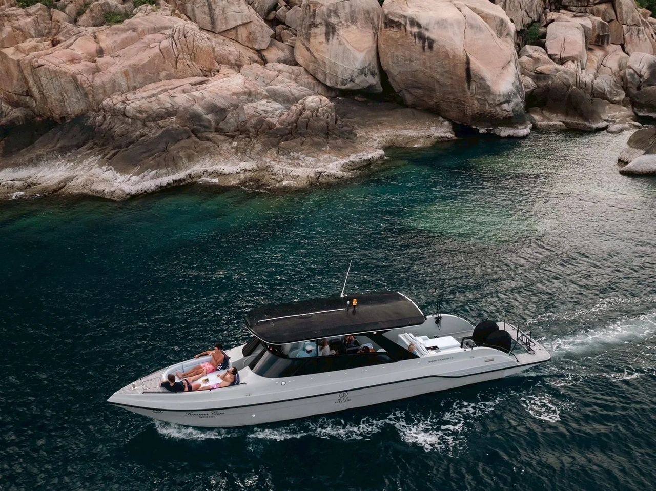 A Blue Voyage speedboat cruising past granite boulders in clear green water