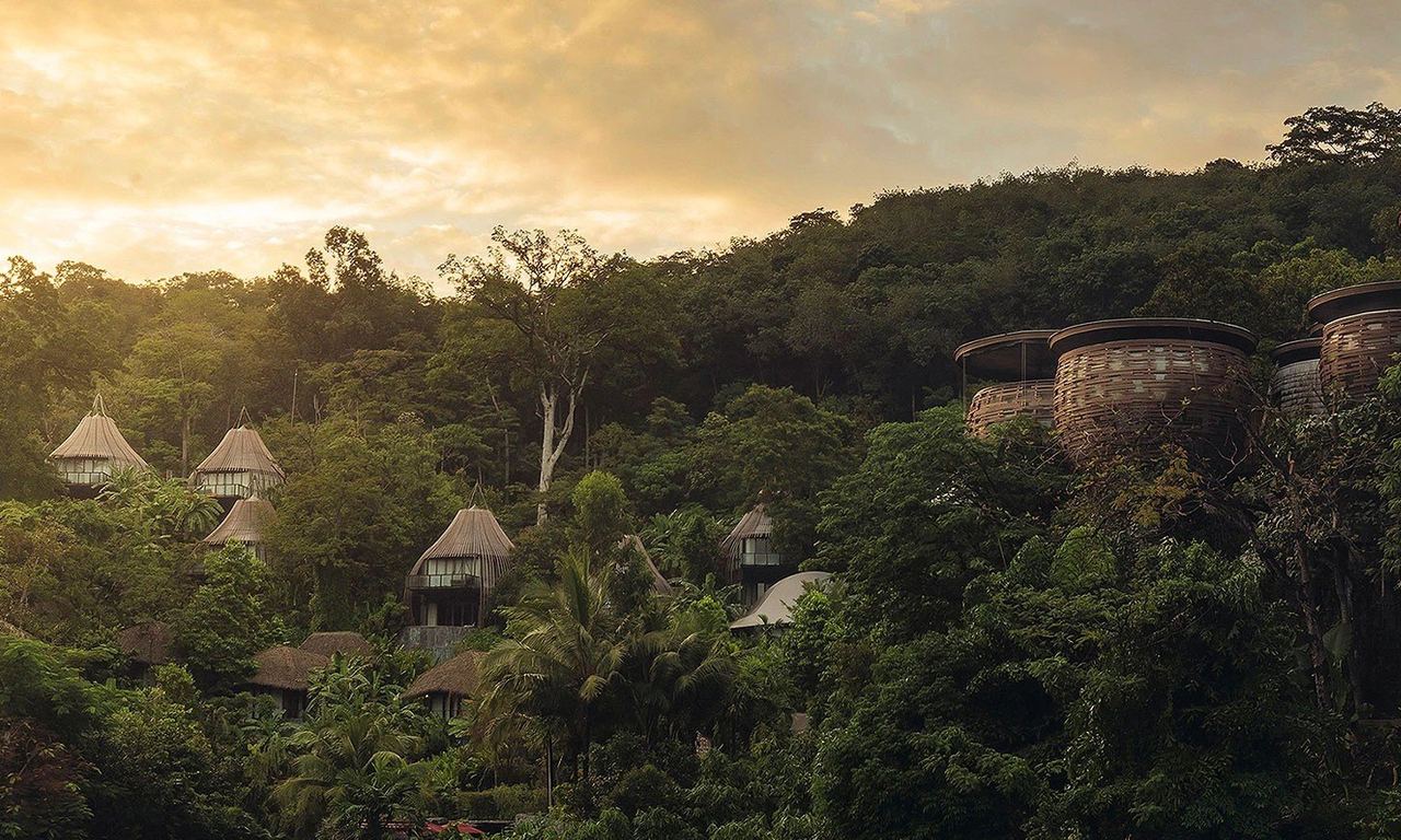 Keemala’s thatched cottages and woven villas on the forested hillside at sunset