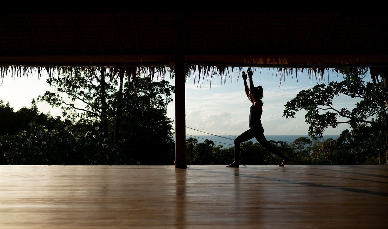A yoga pose in the shala at Absolute Sanctuary, with the trees and the sea beyond