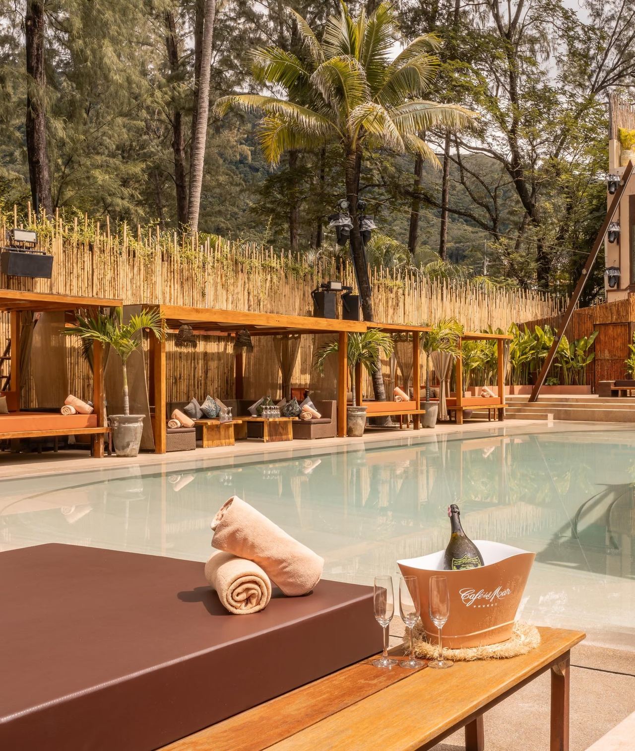 Daybeds under timber pergolas beside the pool at Café del Mar Phuket