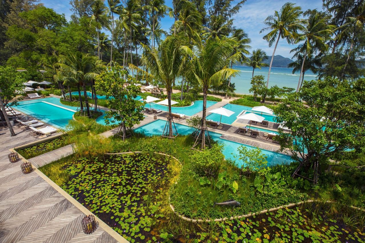 Pools and lily ponds among palms above Emerald Bay at Rosewood Phuket